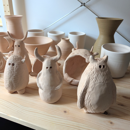 Set of ceramic animal figurines and bowls on a wooden surface with a tiled wall background.